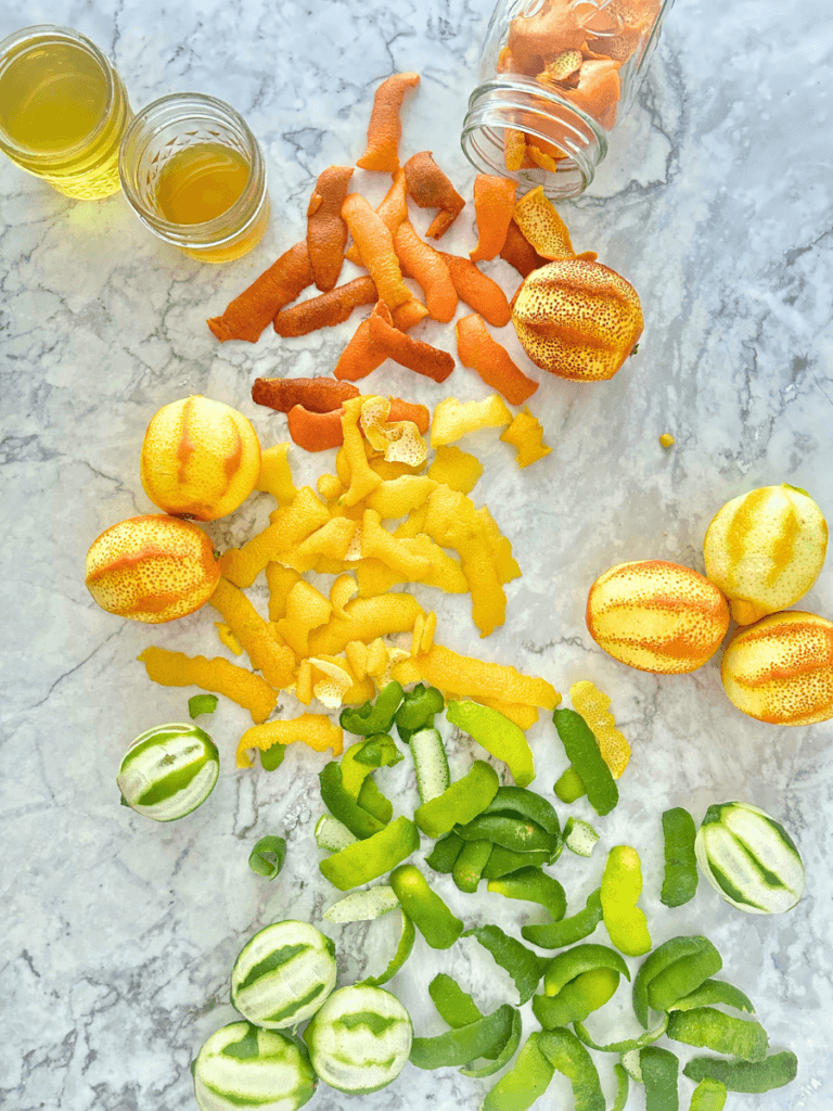 Citrus rinds next to jars of oleo saccharum