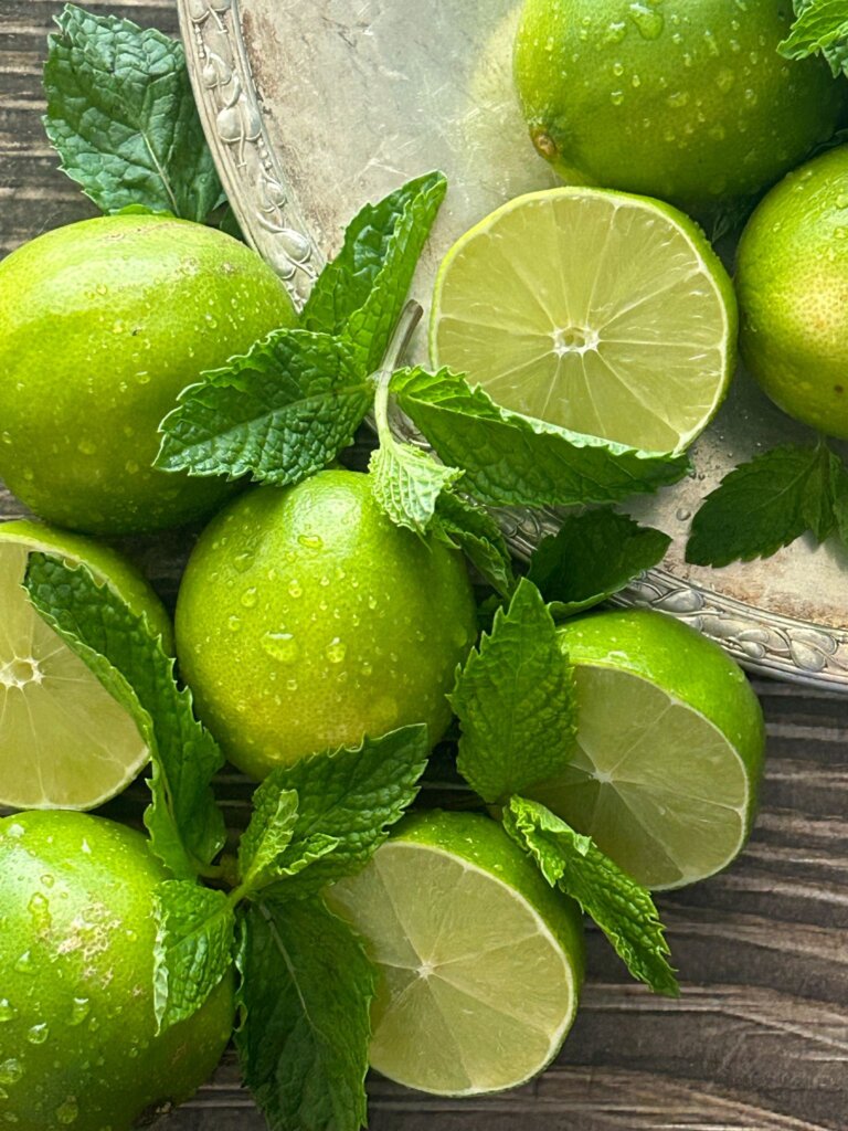 A close up of fresh mint leaves and lime wedges, two of the main ingredients in this fauxjito recipe