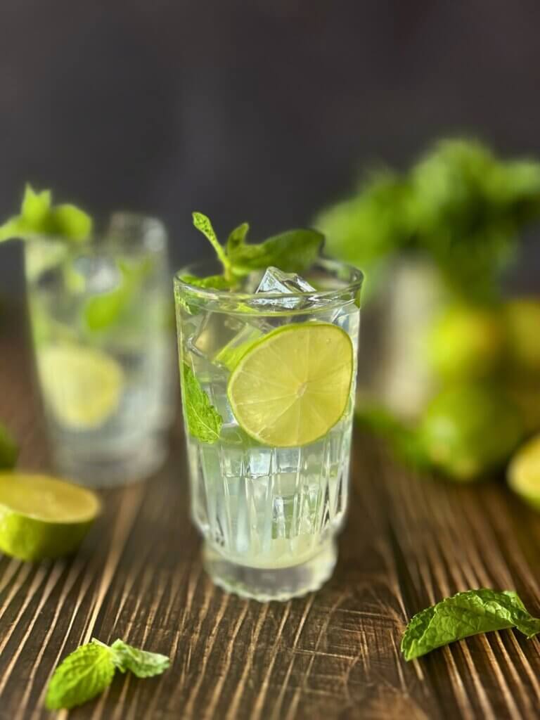 Two mojitos in cut crystal glasses surrounded my lime halves and mint leaves